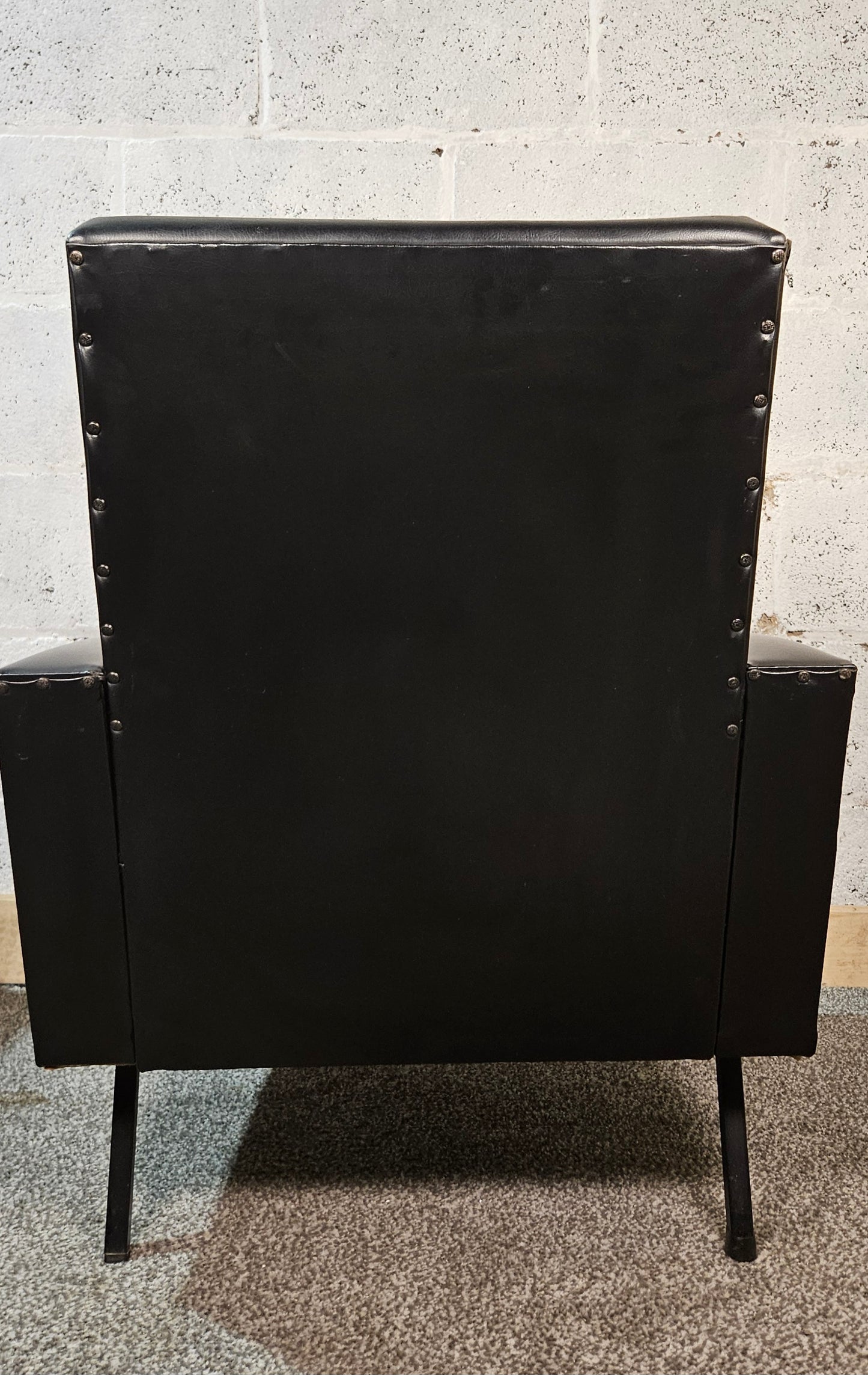 Faux leather Black lounge chair with red seat pad.