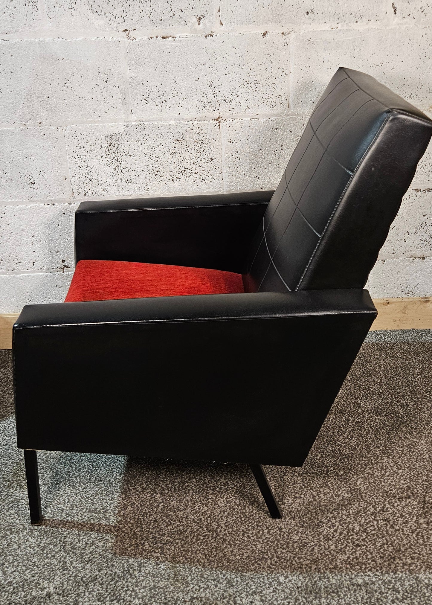 Faux leather Black lounge chair with red seat pad.