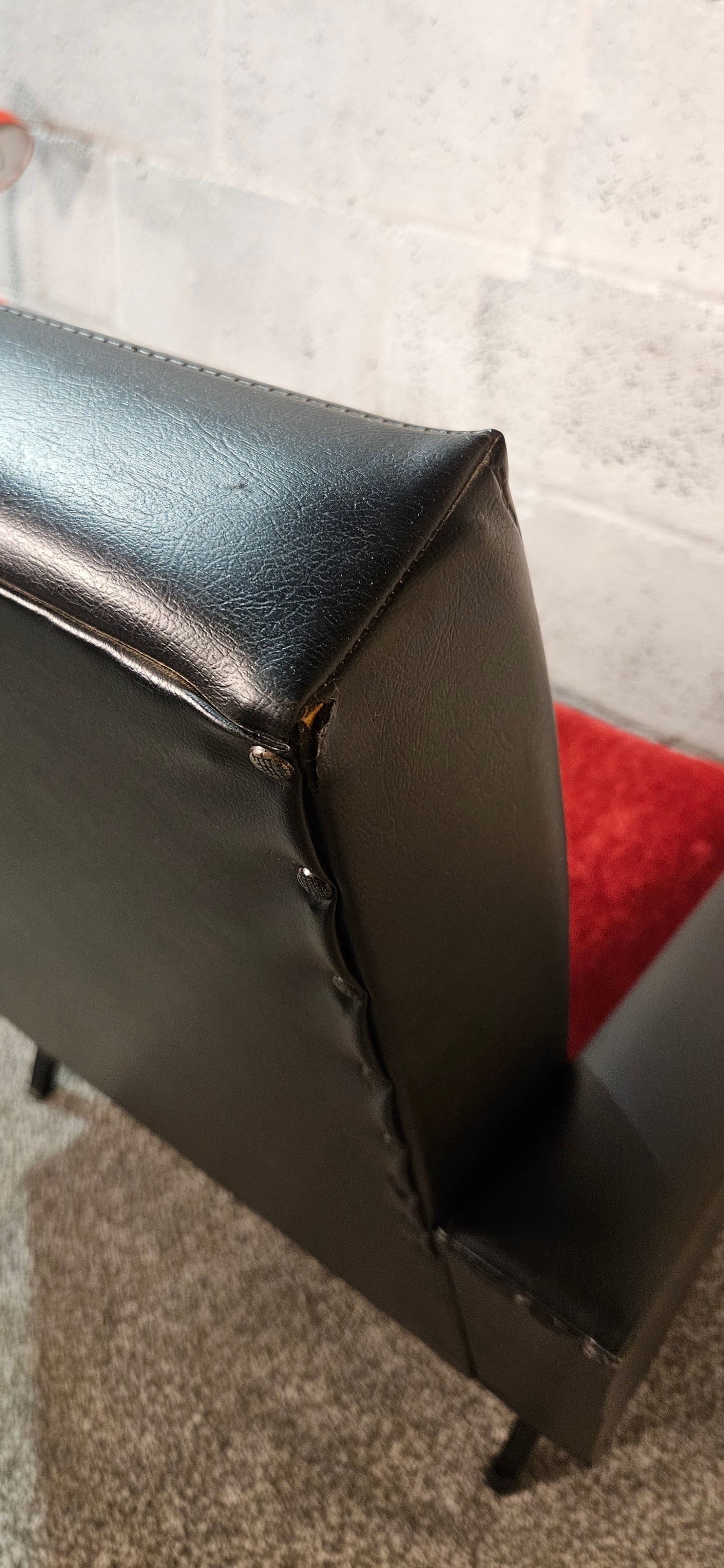 Faux leather Black lounge chair with red seat pad.