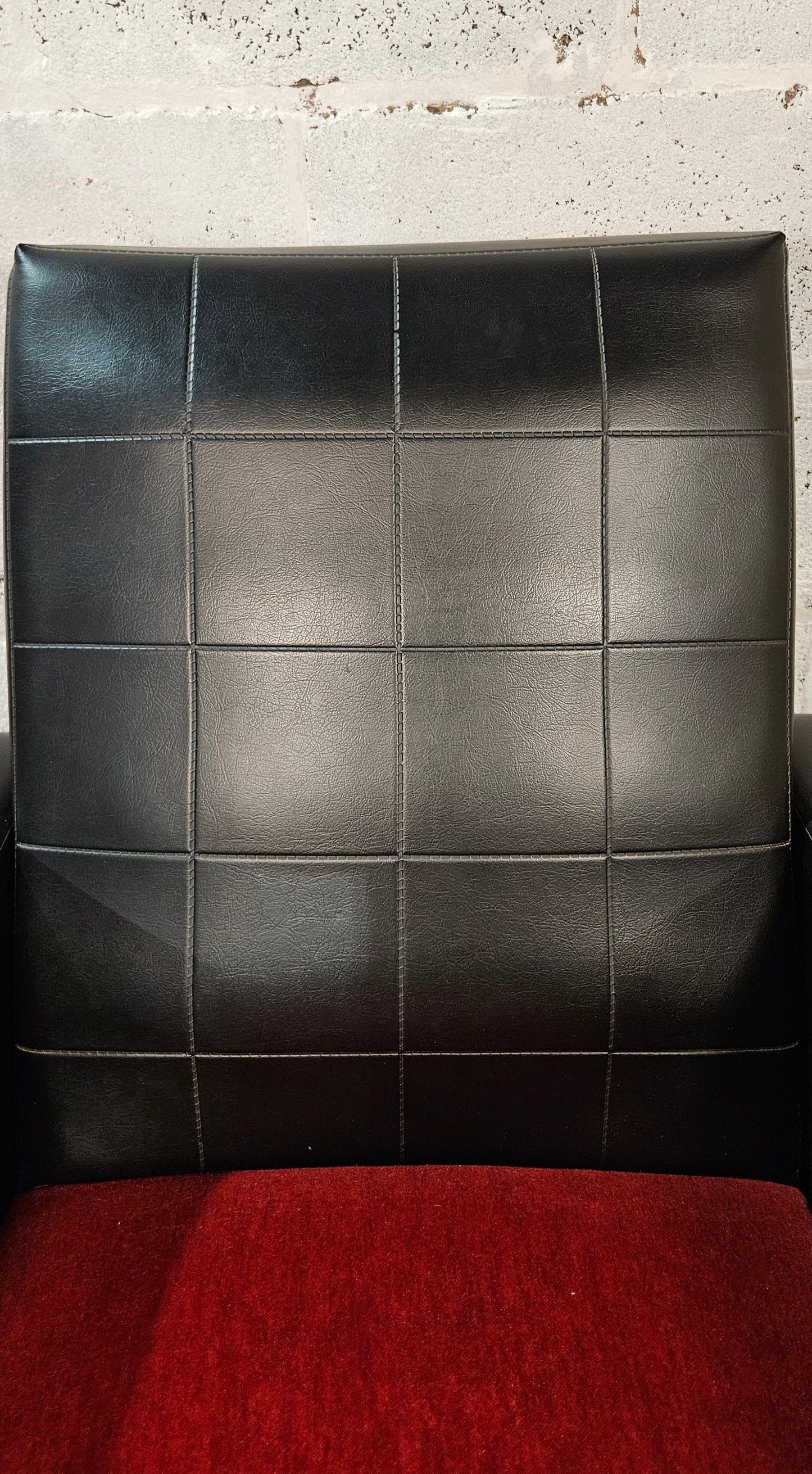 Faux leather Black lounge chair with red seat pad.