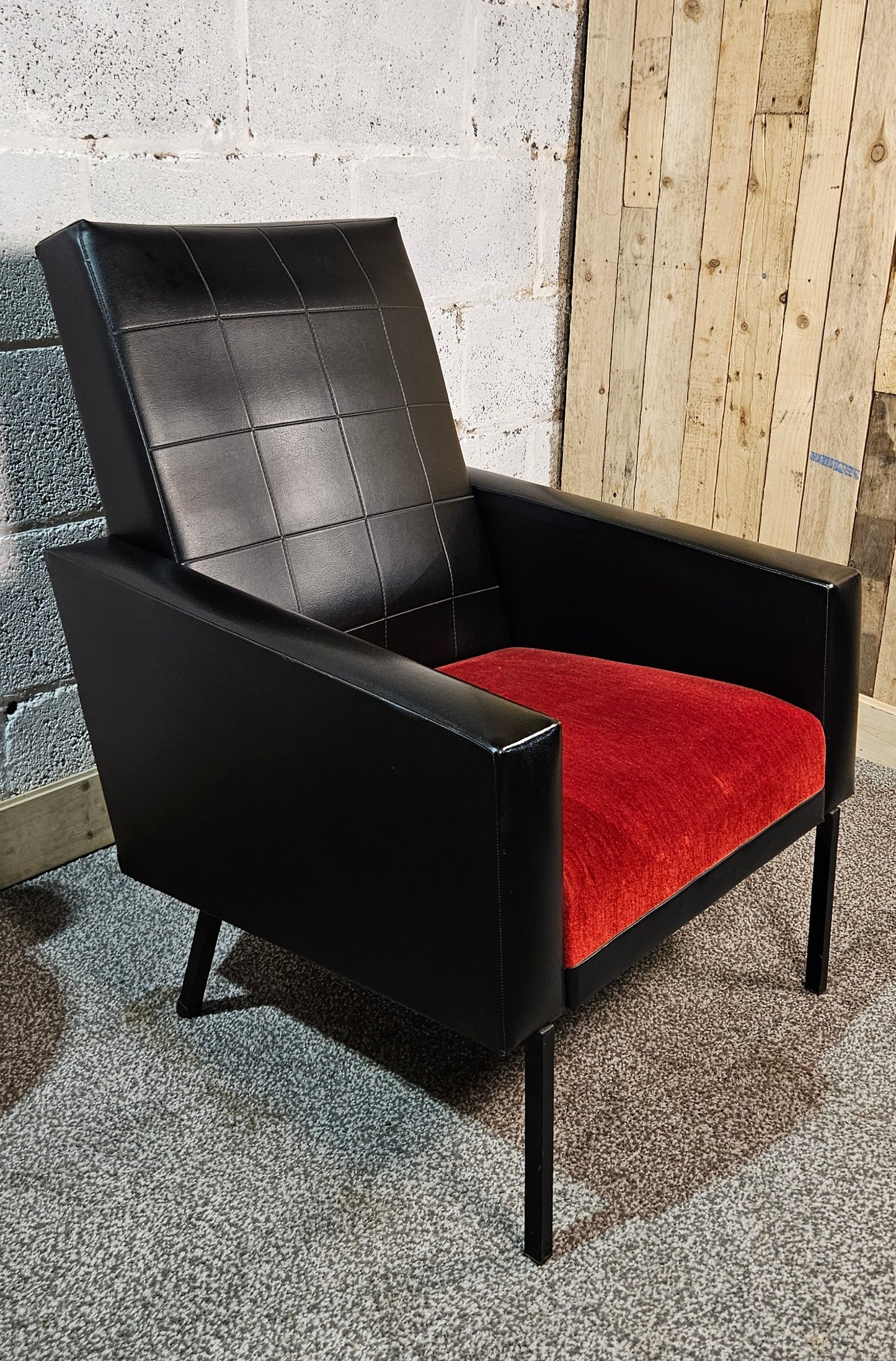 Faux leather Black lounge chair with red seat pad.