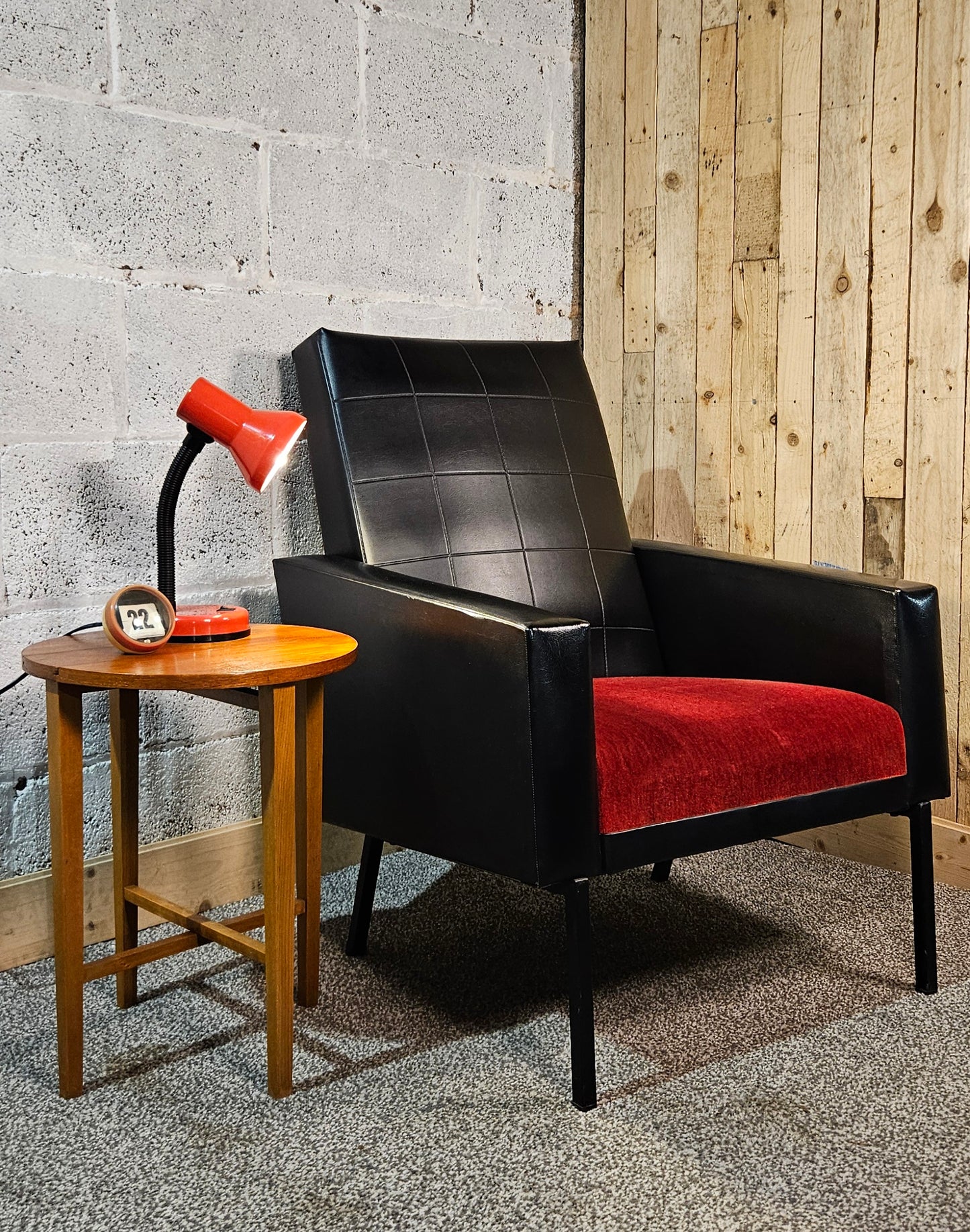 Faux leather Black lounge chair with red seat pad.