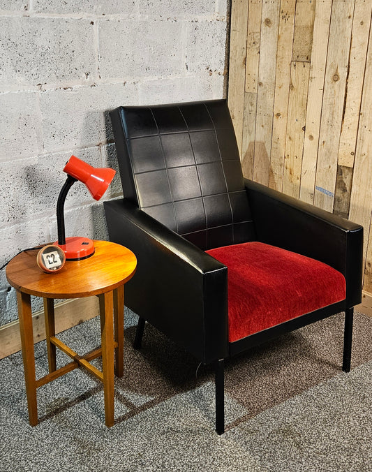 Faux leather Black lounge chair with red seat pad.